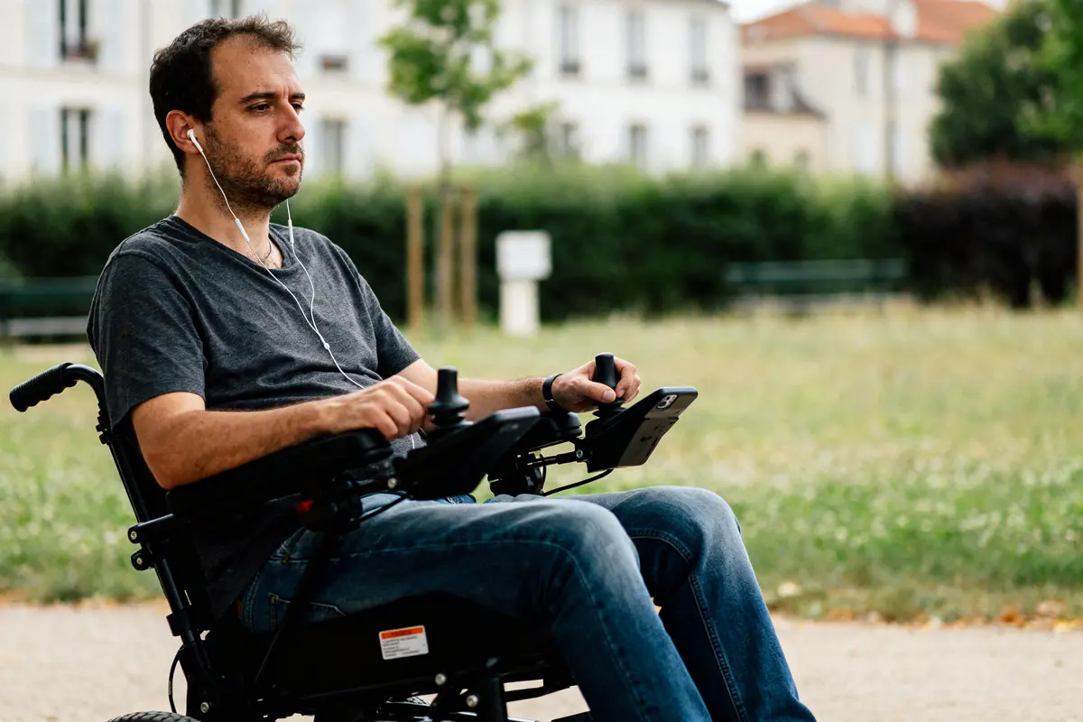 Homme en fauteuil électrique écoutant de la musique, représentant la mobilité des handicapés moteurs