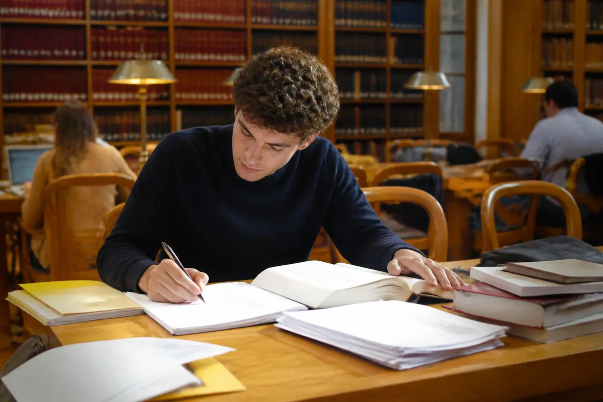 Étudiant concentré sur ses études en bibliothèque avec un but droit académique.