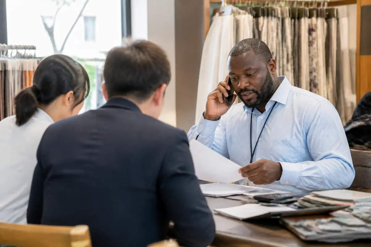 Un commerçant international discute affaires avec deux clients dans un showroom moderne