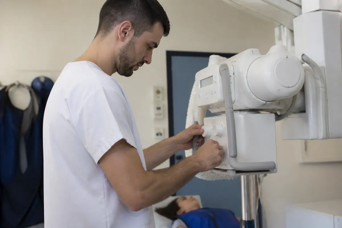 Technicien ajustant appareil radiologique à l'école pour manipulateur radio en formation professionnelle