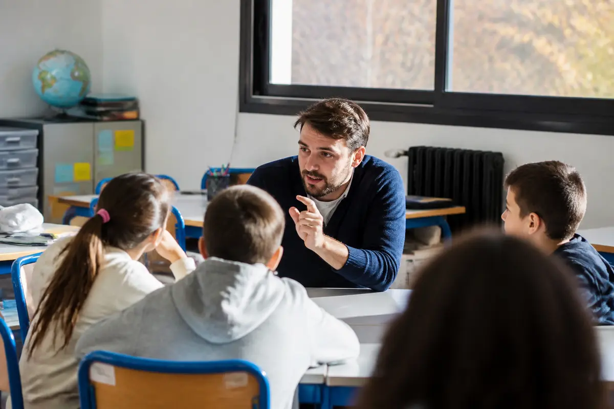 Enseignant discutant avec des élèves, mettant en pratique le référentiel de compétences pour enseignants